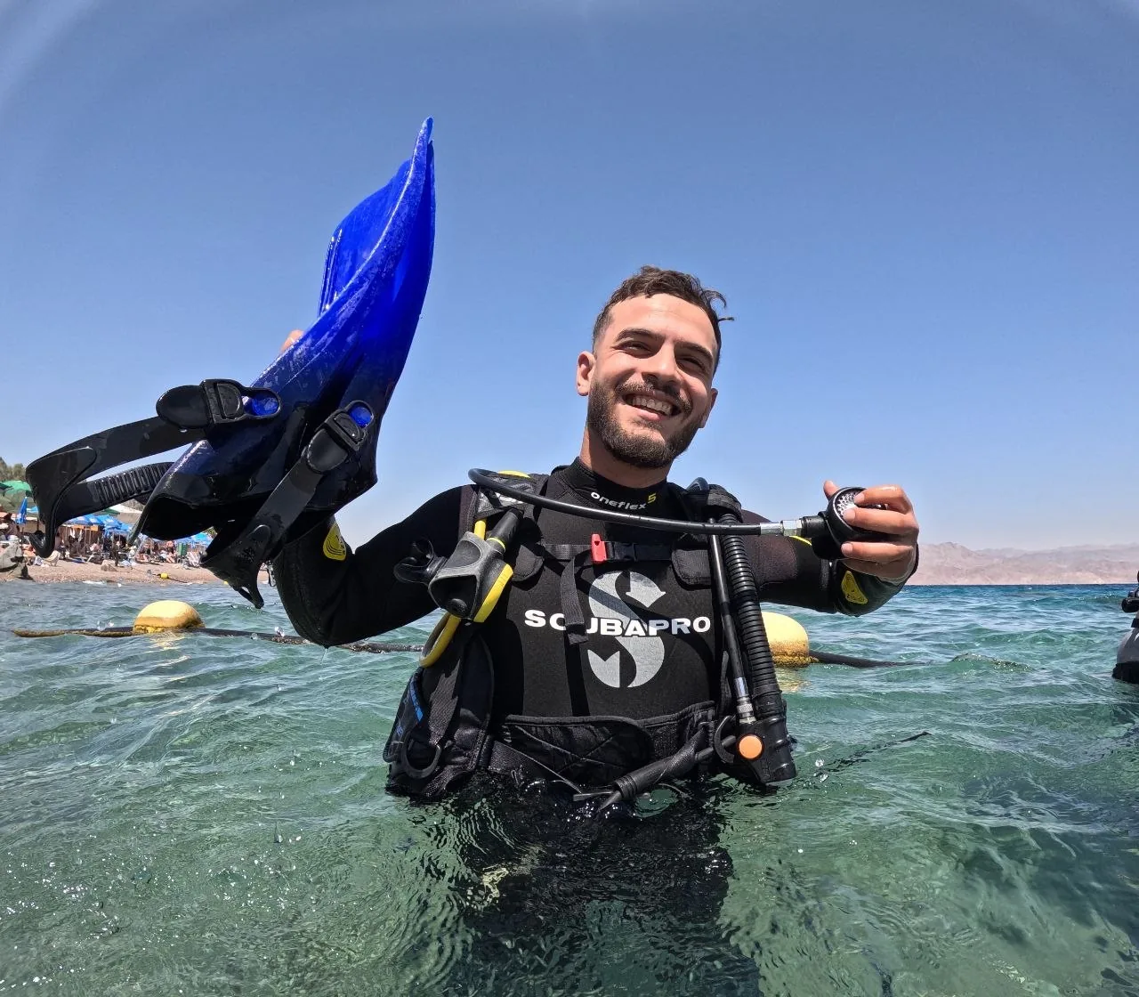 צולל מחייך ומחזיק סנפירים כחולים בים
